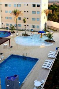 une piscine avec des chaises longues et un grand bâtiment dans l'établissement Encontro das Aguas, à Caldas Novas
