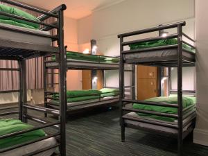 a room with four bunk beds with green sheets at YHA London Earl's Court in London