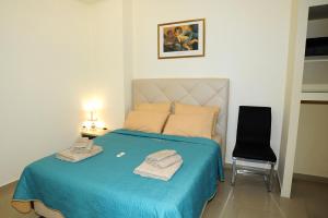 a bedroom with a bed with blue sheets and a chair at Thalia Premium Apartment in Kavála