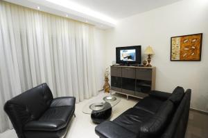 a living room with two leather chairs and a television at Thalia Premium Apartment in Kavála
