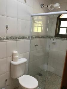 uma casa de banho com um WC e uma cabina de duche em vidro. em Pousada Vison em Itapeva