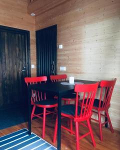 a dining room with a black table and red chairs at Arcticson / pohjosen poika in Syöte