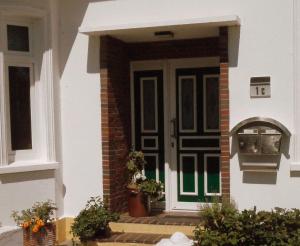 una puerta delantera de una casa blanca con una puerta verde en Frieslands Ferienwohnung en Bockhorn