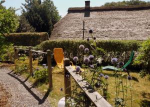 einen Garten mit lila Blumen und einem Strohdach in der Unterkunft Frieslands Ferienwohnung in Bockhorn