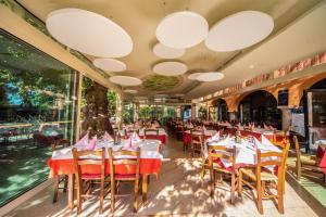 a restaurant with white tables and chairs and large windows at Albergo Al Platano in Caprino Veronese