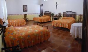 Habitación con 4 camas con sábanas de color naranja y mesa. en Ex-Hacienda San Buenaventura, en San Lorenzo Soltepec