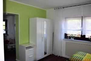 een slaapkamer met groene muren, een witte kast en een raam bij Traum_Fewo 2 Pers_ in Zinnowitz