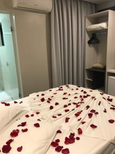 a bed with red roses on a white sheets at Scarpelli Palace Hotel in Sorocaba