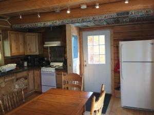 a kitchen with a wooden table and a white refrigerator at Cabins Over Crag Lake in Carcross