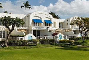 a large white building with blue umbrellas in a yard at The Villas at Fairmont Kea Lani in Wailea