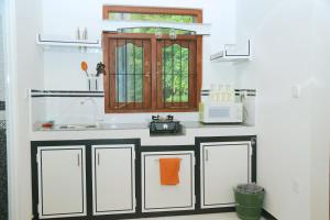 a kitchen with a counter with a sink and a microwave at Happy Spring Guest in Mirissa