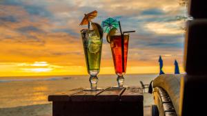 two drinks sitting on a table on the beach at Manuia Beach Resort in Rarotonga