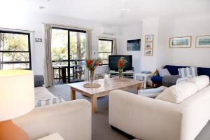 a living room with white furniture and a tv at Refuge Cove On Pittwater in Clareville