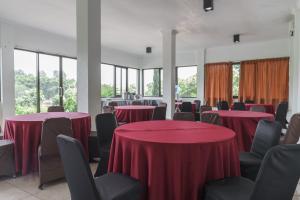 um quarto com mesas e cadeiras vermelhas e janelas em RedDoorz Plus at Hotel Negeri Baru Lodaya Puncak em Bogor