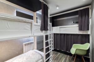 a bedroom with two bunk beds and a green chair at Islander Mini - Hotel in Yuzhno-Sakhalinsk