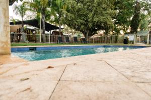 an empty swimming pool with a fence and trees at Wattle Grove Motel in Perth