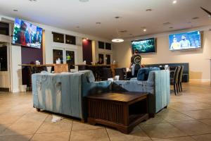 restauracja z niebieskimi kanapami, stołami i telewizorami w obiekcie Wattle Grove Motel w mieście Perth