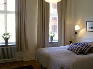 a bedroom with a bed and two windows at Executive Living Södermalm Chic in Stockholm