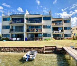 a boat in the water in front of a building at Wharf Lodge River View Apartment in Maroochydore
