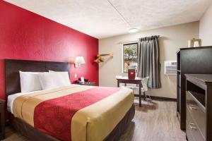 a hotel room with a bed with a red wall at Red Lion Inn & Suites Olathe Kansas City in Olathe