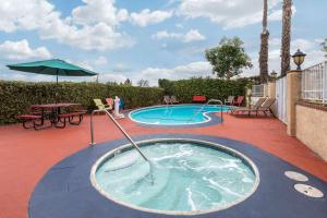 uma banheira de hidromassagem com um guarda-sol ao lado de uma piscina em Quality Inn Lomita-Los Angeles South Bay em Lomita