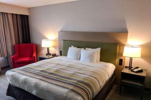 um quarto de hotel com uma cama grande e uma cadeira vermelha em Comfort Inn & Suites em Slidell