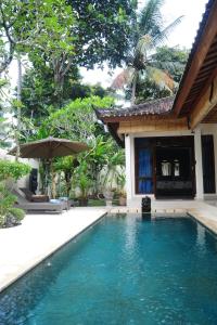 una piscina frente a una casa con sombrilla en Villa Bulan Mas, en Ubud