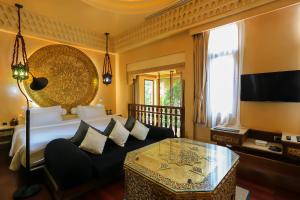 a bedroom with a bed and a couch and a table at Sawasdee Village in Kata Beach