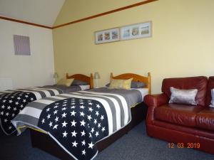 Habitación con 2 camas, silla y sofá en Kindale House, en Helmsdale