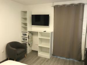 a living room with a tv and a chair at Studio Gallieni in La Châtre