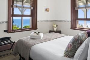 a bedroom with a white bed with two windows at Seal Rocks Lighthouse Cottages in Seal Rocks