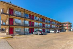 a building with red doors and cars parked in a parking lot at America Best Value Inn in West Memphis