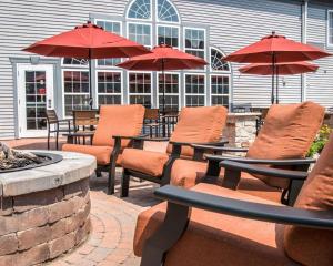 a group of chairs and tables with umbrellas on a patio at Comfort Inn & Suites and Conference Center in Mount Pleasant