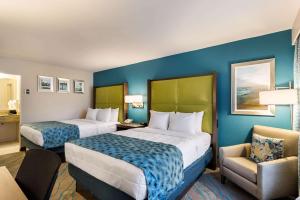 a hotel room with two beds and a chair at Quality Inn Gulfport I-10 in Gulfport +21 photos