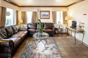 sala de estar con sofá de cuero y mesa de cristal en Rodeway Inn at Nevada State Capitol Carson City en Carson City