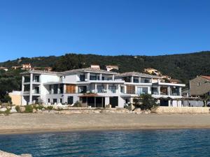 une grande maison blanche sur la plage au bord de l'eau dans l'établissement Residence Capriona, à Porto Pollo
