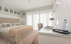 Casa Laranja Boutique House في كاسكايس: غرفة نوم بيضاء مع سرير وطاولة زجاجية