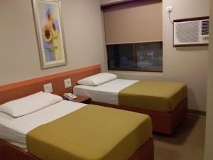 a hotel room with two beds and a window at Sai Palace Express(Shirdi) in Shirdi