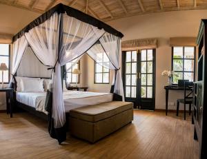 高尔Tabula Rasa Resort & Spa的一间卧室配有天蓬床和沙发