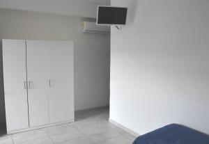 a room with white cabinets and a tv on a wall at Tindari Village Camping in Furnari