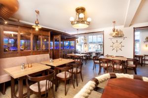 un restaurant avec des tables et des chaises en bois ainsi que des fenêtres dans l'établissement Hotel Villa Waldfrieden, à Sellin