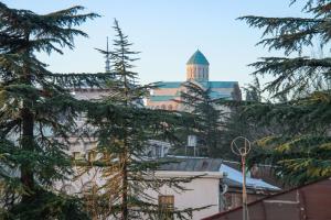 a building with a tower in the background with trees at Onestep in Kutaisi