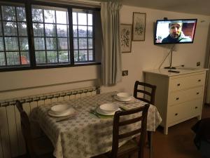 a dining room with a table and a tv on the wall at Villetta Gabriella in Impruneta