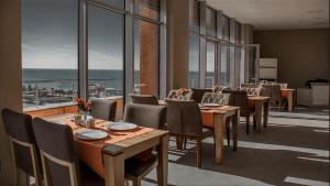 a restaurant with tables and chairs and a view of the ocean at Legend Business Hotel Batumi in Batumi