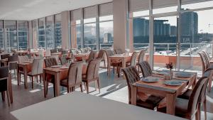 a dining room with tables and chairs and windows at Legend Business Hotel Batumi in Batumi