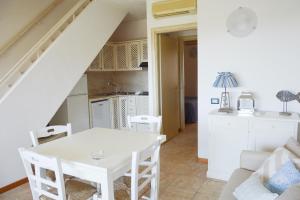 cocina y sala de estar con mesa blanca y sillas en Sa Tirìa en Chia
