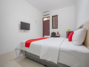 a bedroom with a large white bed with a red pillow at RedDoorz @ Kertajaya Surabaya in Surabaya
