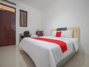 a bedroom with a large white bed with a red blanket at RedDoorz @ Kertajaya Surabaya in Surabaya +7 photos