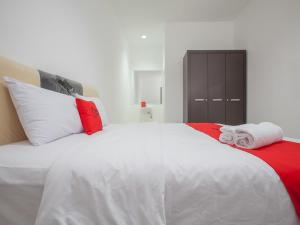 a white bed with red and white pillows on it at RedDoorz @ Kertajaya Surabaya in Surabaya