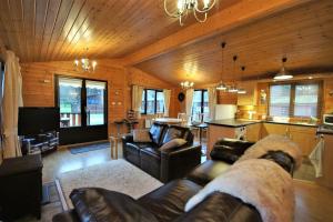 a living room with leather couches and a kitchen at Ben Lomond Lodge in Rowardennan